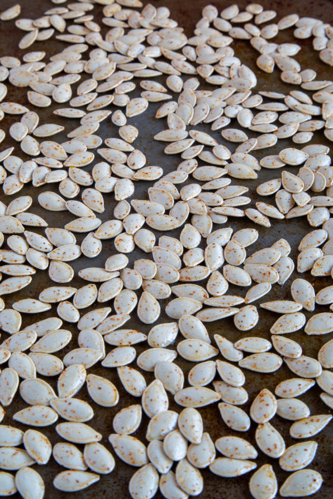 Raw pumpkin seeds coated in oil and seasoning for Roasted Pumpkin Seeds