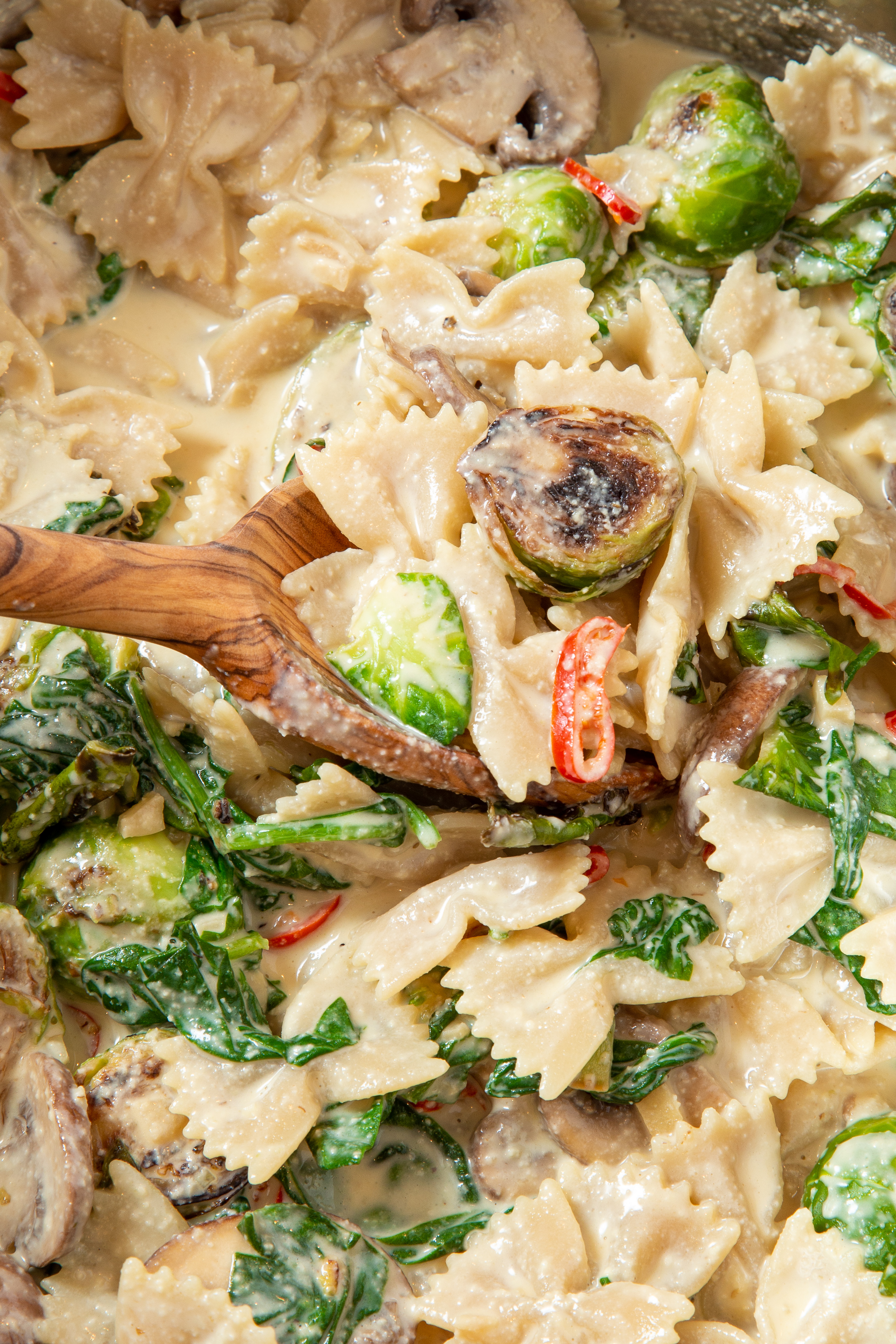 Sautéed vegetables mixed in with creamy pasta in pot