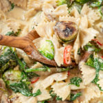 Sautéed vegetables mixed in with creamy pasta in pot