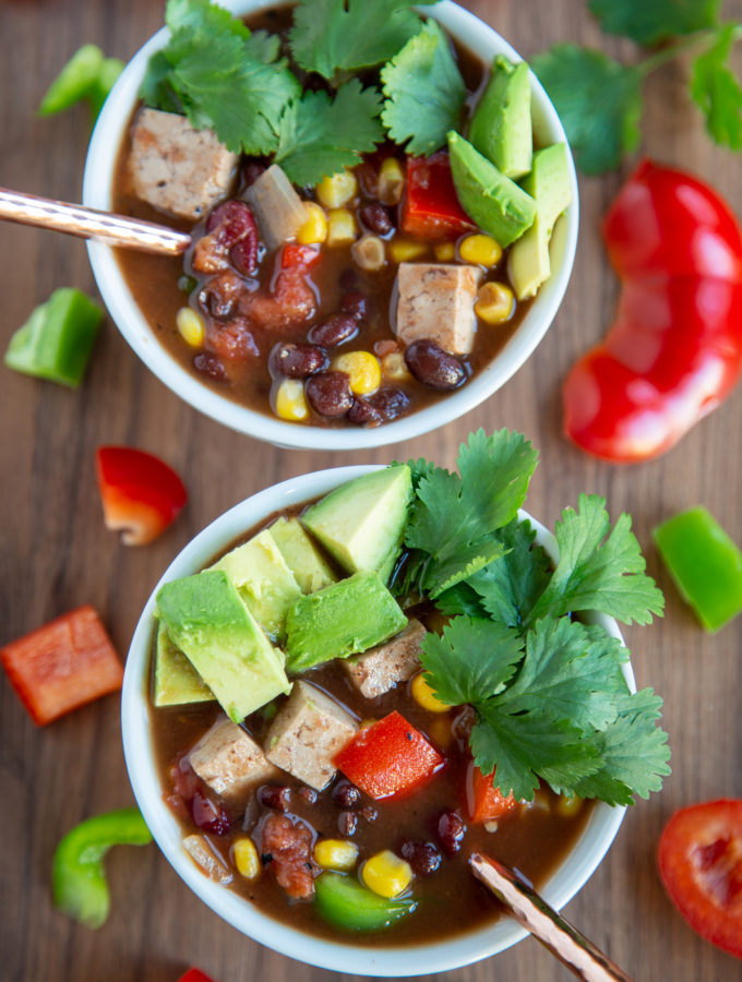 Overhead shot of two bowls of Vegan Chili topped with avocado and cilantro